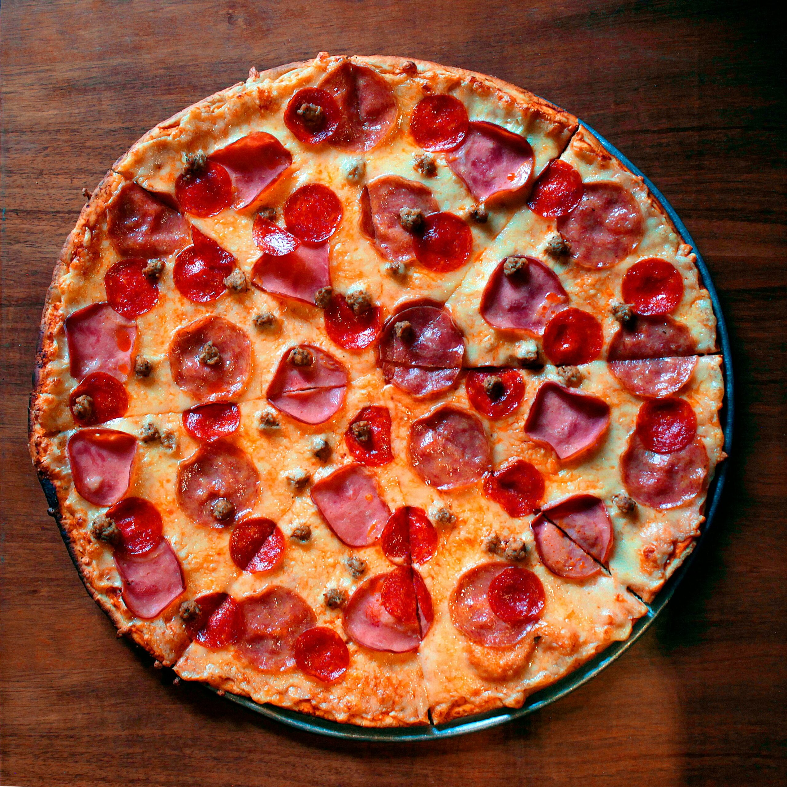 A freshly baked vegetable pizza topped with colorful vegetables on a rustic wooden table